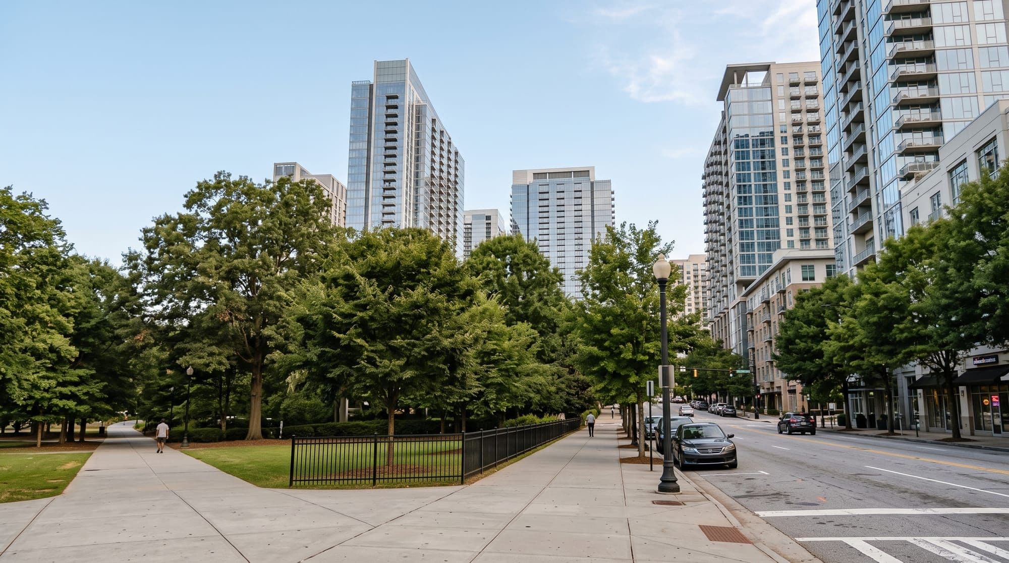 Modern glass high-rise towers along a tree-lined Midtown Atlanta street